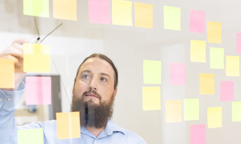Developer at Glass Board Developer arranges Post-its on a glass board.
