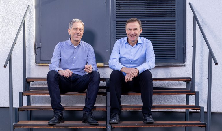 Abbildung der Geschäftsführer Nicholas Lemke und Wilhelm Tegethoff Die Geschäftsführer Nicholas Lemke und Wilhelm Tegethoff von TLK-Thermo sitzen zusammen auf einer Treppe