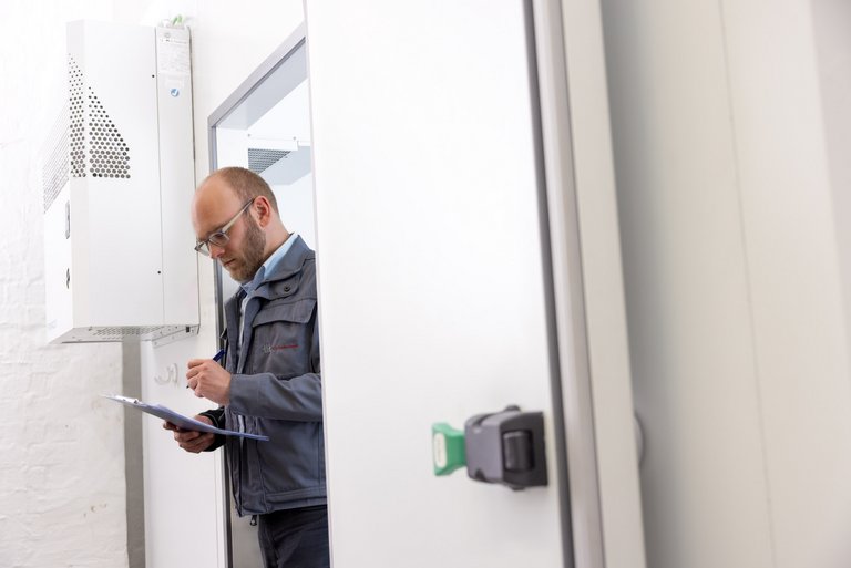 An engineer checks his notes on the measurement of a domestic heat pump in a climate chamber.