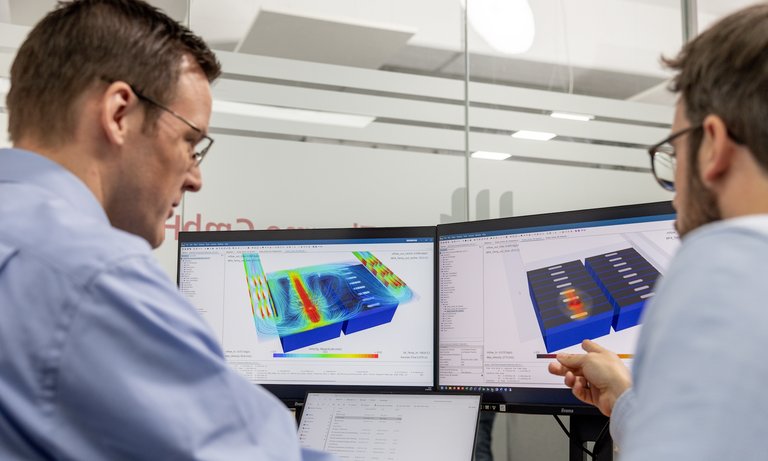 Zwei Mitarbeiter diskutieren die Modellierung von Batterien Zwei Mitarbeiter diskutieren die Modellierung von Batterien anhand von CFD-Darstellungen